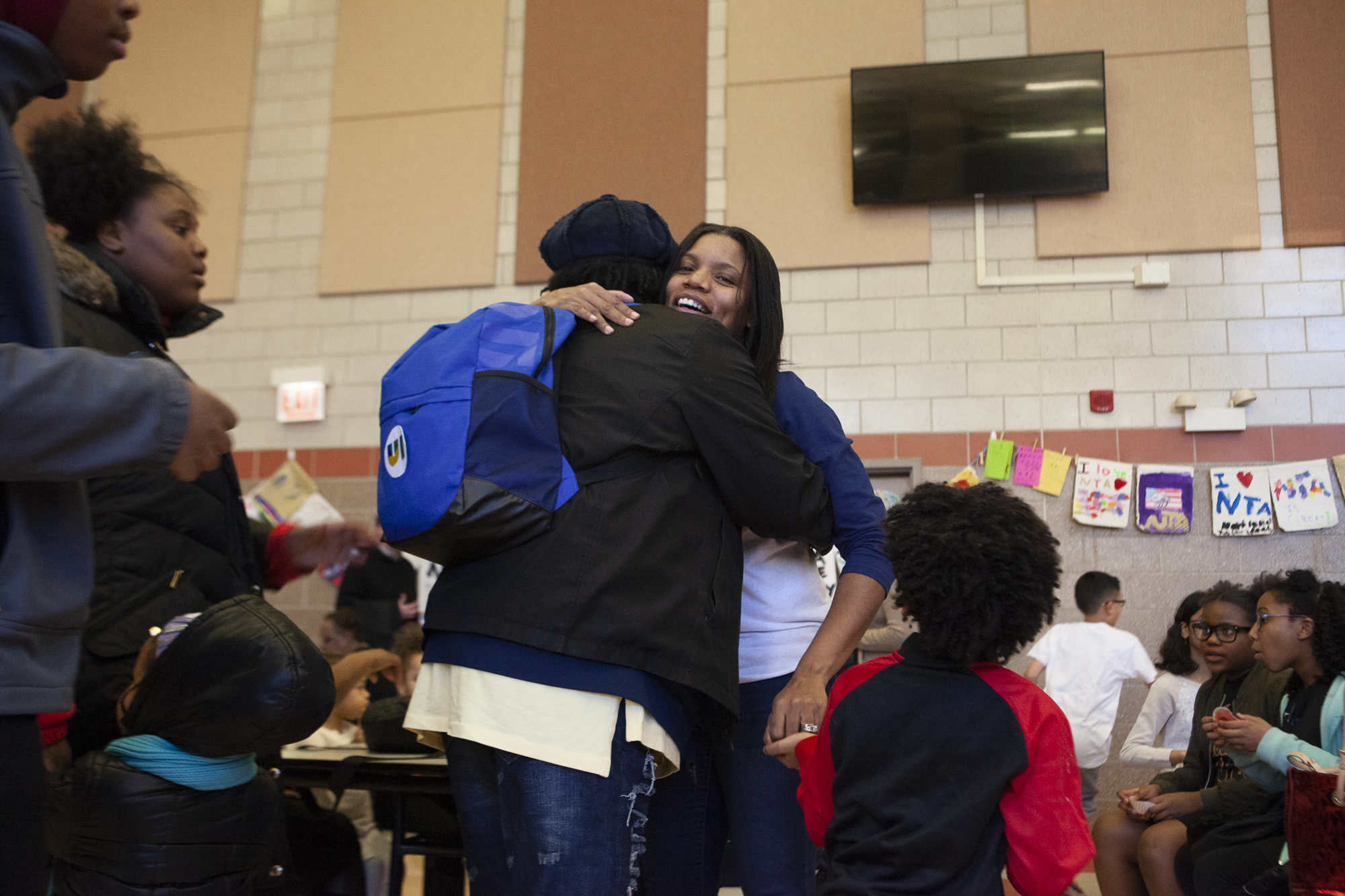 National Teacher's Academy assistant principal Teneka Brooks, center, hugs a student white holding on to her son's hand at NTA on Saturday.