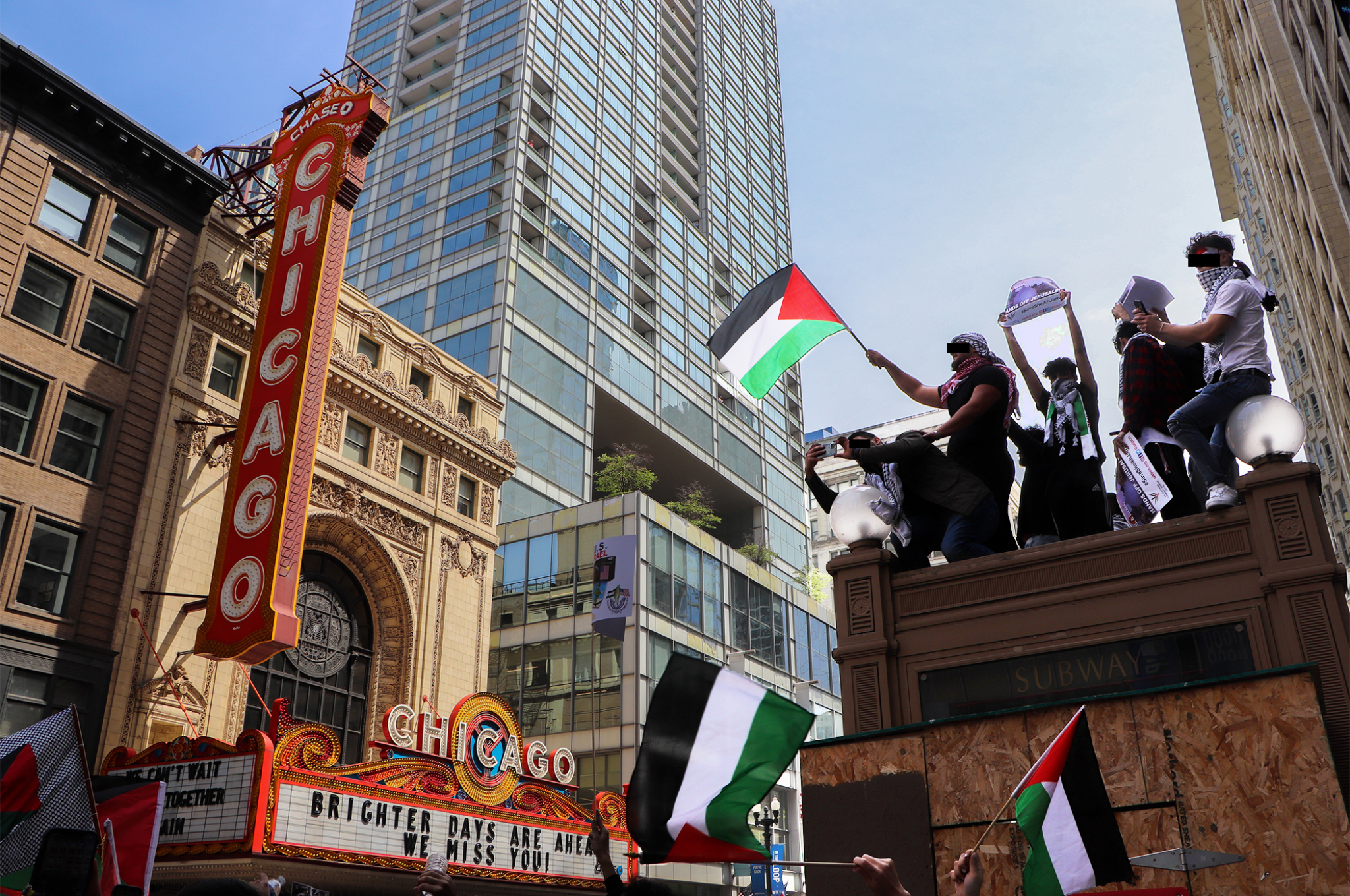Some demonstrators scale an entrance to the ‘L’ to wave Palestinian flags above the group as they march on May 16, 2021 in Chicago. (Madison Muller/South Side Weekly)