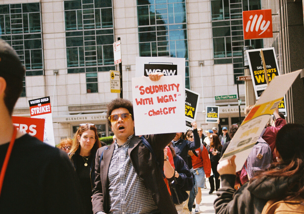 A protester at a WGA rally holds a sign that reads, "'Solidarity with WGA!' -ChatGPT" on May 17, 2023 in Chicago, Illinois. Photo Credits: Jocelyn Martínez-Rosales