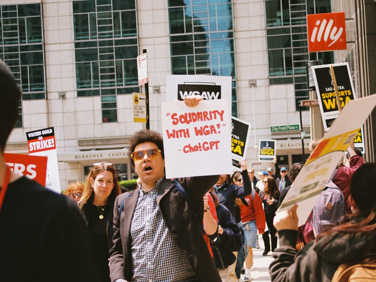 A protester at a WGA rally holds a sign that reads, "'Solidarity with WGA!' -ChatGPT" on May 17, 2023 in Chicago, Illinois. Photo Credits: Jocelyn Martínez-Rosales