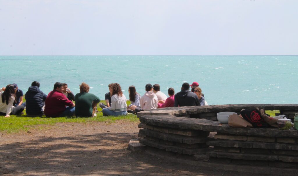 Picnic-goers sit next to a fire pit at Promontory Point.
